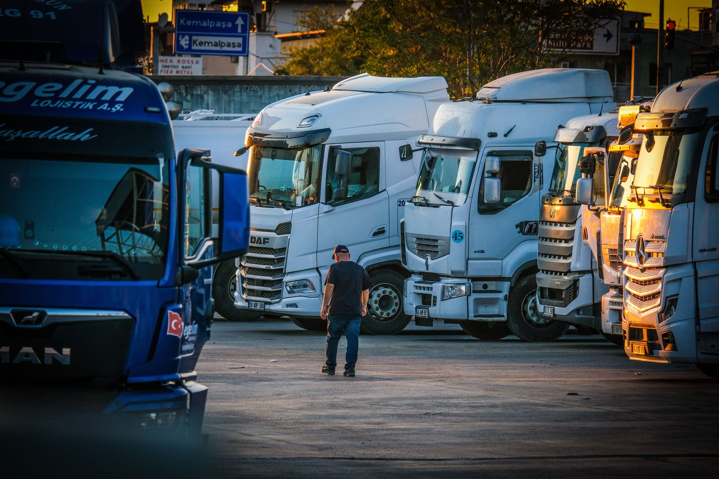 Driver walking through a fleet of parked semi trucks at sunset