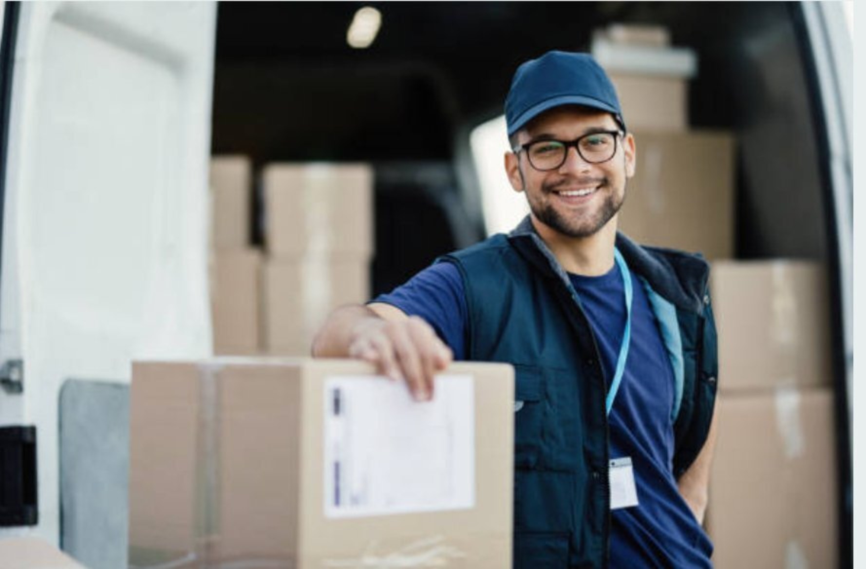 Smiling delivery driver loading a package into a van